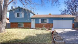 A blue house with a white door and a driveway.