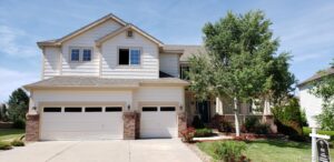 A white house with two garage doors and trees.