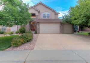 A large house with a driveway and trees in front of it.